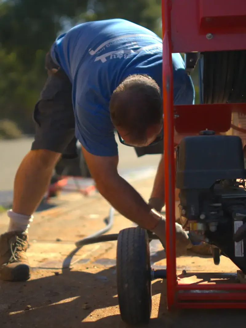 North Bay crew member beside plumbing service equipment