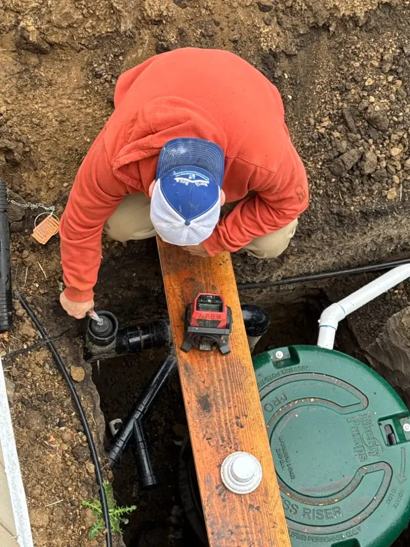 Crew member working at a below-ground plumbing access point
